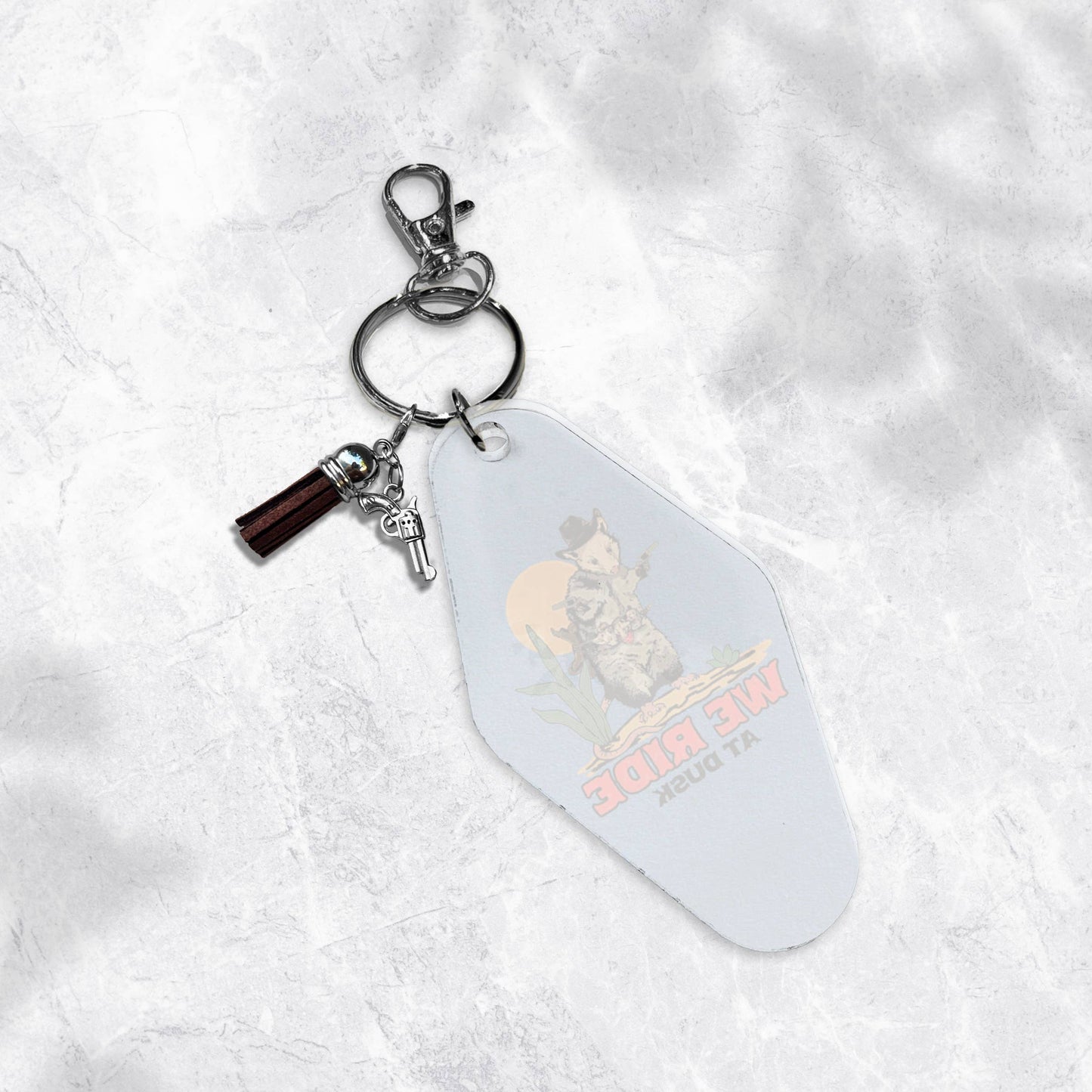 We Ride at Dusk- Opossum Cowboy Motel Tag Keychain
